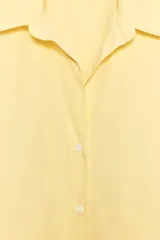 Camisa amarilla de popelina de algodón, con cuello solapa, escote en pico, manga larga con puños y cierre frontal con botones.