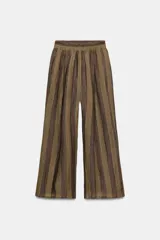 Pantalón ancho de lino 100%, color marrón y verde oliva, con rayas verticales. Presenta cintura elástica y bolsillos delanteros ocultos en la costura lateral.