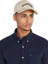 Gorra de béisbol beige de algodón con logo de Tommy Hilfiger bordado en azul en el frente y bandera de la marca bordada en el lateral.