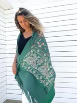 Chal verde esmeralda de cachemira con bordados de flores y paisley en tonos beige, rojo y celeste. Tiene flecos en los bordes.