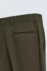 Pantalón de traje color verde oliva oscuro, corte slim fit, con pinzas frontales y bolsillos de doble vivo en la parte trasera.