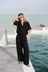 Pantalón negro de tiro alto con cintura elástica ajustable con cordones, bolsillos delanteros y pernera ancha.