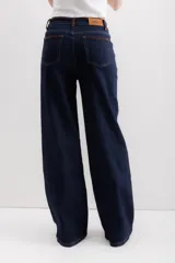 Pantalón de jean azul oscuro, de corte wide leg, con cintura alta y detalles de costuras en marrón.