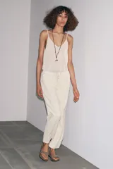 Pantalón culotte color crudo, de tiro medio, cintura elástica ajustable con cordones y bolsillos laterales ocultos en la costura.