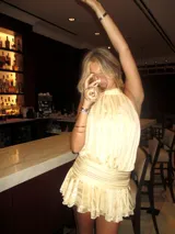 Minivestido color crema con cuello halter, espalda descubierta y falda con volados.