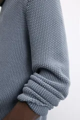 Sweater azul de punto con textura, corte holgado, cuello redondo y mangas largas con puños acanalados.