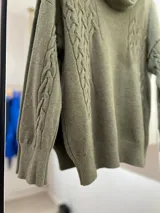 Sweater verde seco de corte recto con cuello caído, punto trenzado en la parte delantera y terminaciones en punto elástico en puños y bajo.