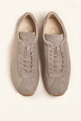 Zapatillas deportivas de cuero color borgoña con detalles en gamuza al tono, cordones finos y suela de goma blanca.