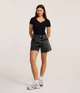 Short de jean estilo mom, color negro con efecto marmoleado (acid wash). Presenta tiro alto, trabillas para cinturón, cierre tradicional, bolsillos y ruedo cortado sin remate.