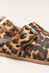 Sueco destalonado de cuero vacuno color negro, con hebilla ajustable dorada y detalles de tachas doradas.