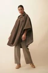 Poncho unisex de lana fina color marrón claro, con cuello polo, cartera con broches a presión y bolsillo ojal.