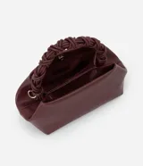 Cartera pequeña color borgoña, con asa corta trenzada y correa larga ajustable y desmontable. Cierre superior con broche imantado. Interior forrado con bolsillo.