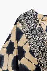 Vestido amplio estilo caftán con estampado geométrico en tonos beige y azul, escote en pico con lentejuelas y manga ancha por debajo del codo. Cintura ajustable con cordones con borlas.