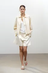 Cazadora tipo bomber color crema confeccionada en hilatura con mezcla de algodón. Cuello solapa y manga larga. Bolsillos delanteros. Forro interior a tono. Bajo ajustable. Cierre frontal con cremallera metálica.