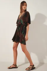 Vestido corto con escote en V y mangas cortas amplias, con elástico fruncido en la cintura. Presenta un teñido tie-dye en tonos marrón oscuro y verde azulado, con bordado de hilos de lurex en el escote.