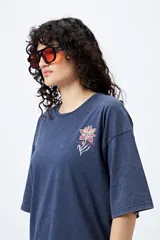 Remera azul con efecto gastado, corte holgado y estampado pequeño de flor en el pecho.