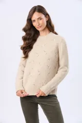 Buzo tejido de abrigo color beige, con cuello redondo y mangas largas. Presenta un delicado diseño bordado en el frente con pequeños motivos en tonos pastel.