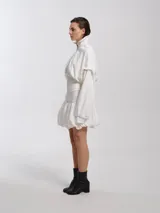 Chaleco estilo bomber blanco, forrado con felpa, con cuello alto y faja ancha en el bajo. Presenta mangas desmontables, creando un efecto de chaleco con mangas abullonadas.