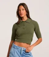 Blusa de punto texturizado color verde oliva, con cuello polo, mangas cortas y puños con botones.