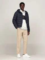 Campera Tommy Hilfiger acolchada color azul marino, con capucha fija ajustable con cordón, cierre de cremallera frontal, dos bolsillos laterales y parche engomado con el logo de la marca en la manga.