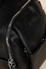 Mochila negra de cuero sintético con diseño minimalista, formato compacto y estructura blanda. Incluye bolsillo delantero con broche y cierre metálico superior con tiradores largos.