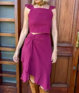 Falda corta color fucsia, confeccionada en tusor de algodón, con detalle de jareta fruncida en un lateral y vuelo asimétrico.