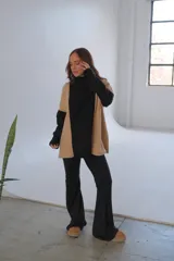 Conjunto de viscosa con felpa, compuesto por un buzo de cuello alto con mangas largas en color negro y paneles laterales en color beige, y un pantalón Oxford negro.