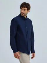Camisa de vestir azul marino, de corte clásico, con cuello abotonado, manga larga y bolsillo en el pecho.