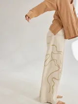 Pantalón de lino color beige con bordado artesanal de líneas onduladas en color marrón.