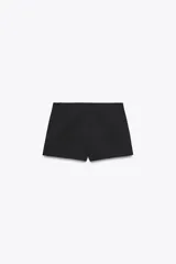 Shorts tiro bajo color negro con bolsillos delanteros. Cierre frontal con cremallera y ganchos metálicos.