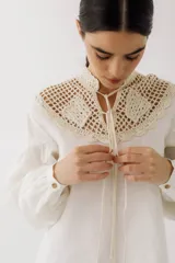 Blusa color ladrillo con cuello alto de crochet y lazos para ajustar. Mangas largas abullonadas con puños elásticos.