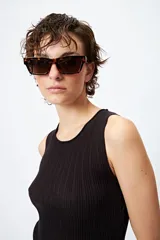 Musculosa de punto color beige, con textura acanalada y detalle de trenzado lateral ajustable.