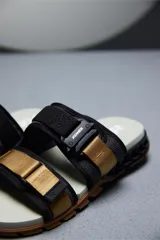 Sandalias Kenner Rakka A-Just con tiras de ajuste en color negro y dorado.