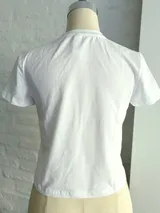 Remera blanca de algodón con estampado de una flor lila en el centro.