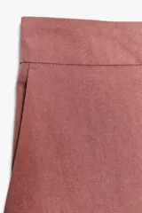 Pantalón de vestir color beige, de tiro alto, con cintura elástica en la parte trasera, bolsillos delanteros y falsos bolsillos de vivo en la parte trasera.