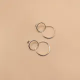 Par de aros de plata 925 con cierre a presión, compuestos por un círculo pequeño y un círculo grande entrelazados.