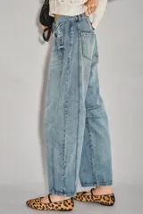 Jean de denim rígido azul claro, tiro medio-alto, con calce holgado y piernas anchas que se estrechan ligeramente hacia el tobillo. Presenta pinzas en la zona de las rodillas y un recorte en el lateral.