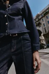 Jeans de mezclilla azul oscuro, tiro medio, corte recto y slim. Presenta costuras verticales marcadas en el frente de ambas piernas y viene con un cinturón de cuero marrón.