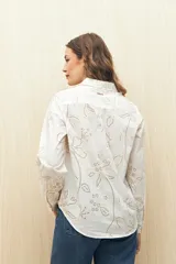 Camisa blanca de manga larga confeccionada en algodón liviano con calados florales. De corte clásico y botones frontales.