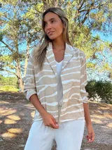 Camisaco de seda con estampado de rayas horizontales irregulares en tonos tierra y crudo. Posee cuello solapa y botones frontales.