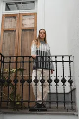 Sweater de punto con cuello alto y diseño a rayas en tonos grises, de manga larga y corte suelto.