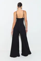 Mono largo negro de punto de viscosa acanalado, con pernera ancha, cintura ajustada, abertura en el busto, tirantes finos y ballenas en la cintura. Se cierra con cremallera en la espalda.