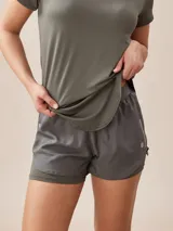 Short deportivo verde militar con calza interna, cintura elástica y logo estampado en la pierna.