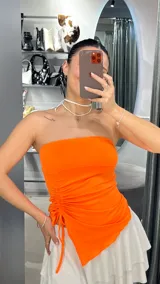 Top bandeau naranja con detalle de frunce lateral y tiras ajustables.