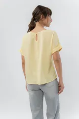 Remera blanca de viscosa liviana, con escote redondo y mangas cortas con vuelta.