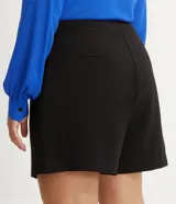 Bermuda de crepé color rojo, con pliegues frontales y botones decorativos en los bolsillos laterales.