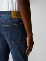 Pantalón de jean azul oscuro, corte slim, con bolsillos delanteros y traseros, cierre con cremallera y botón.