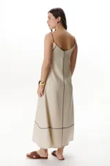 Vestido largo color crudo con breteles finos y costuras a la vista en color azul.