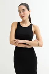 Vestido largo negro ajustado al cuerpo, sin mangas y con cuello redondo. Presenta una abertura lateral en el ruedo.