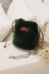 Bolso de mano verde oscuro de piel sintética con cierre de cordón ajustable, asa de cadena plateada y parche de cuero con el logo de la marca.